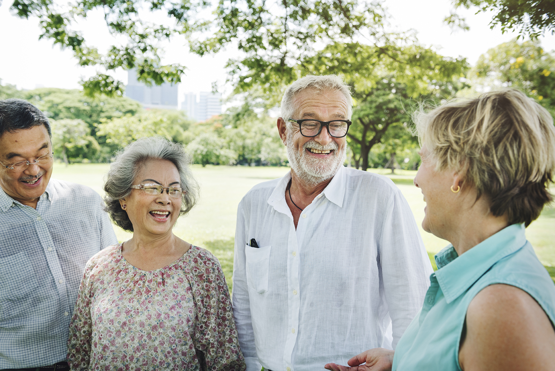 Zwei Damen und zwei Damen stehen im Park zusammen und plaudern