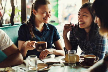 Menschen sitzen bei Kaffee und Kuchen zusammen