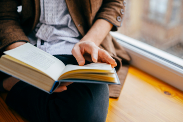 Eine Person hält ein offenes Buch in der Hand 