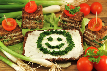 Gesundes Frühstück, Brot mit Schnittlauch-Smiley, daneben Tomaten.